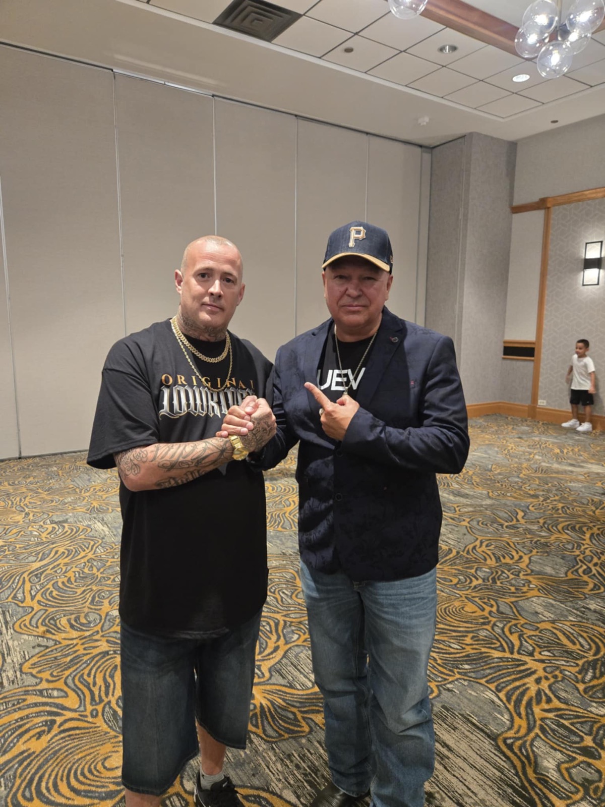 Two men posing together in a hotel ballroom