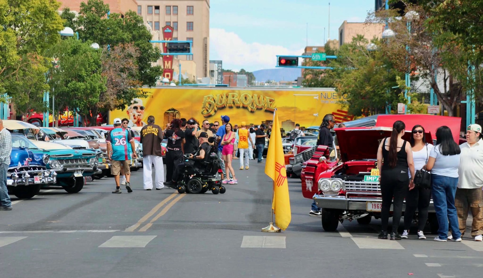 Lowrider car show on a downtown Albuquerque street with the New Mexico flag