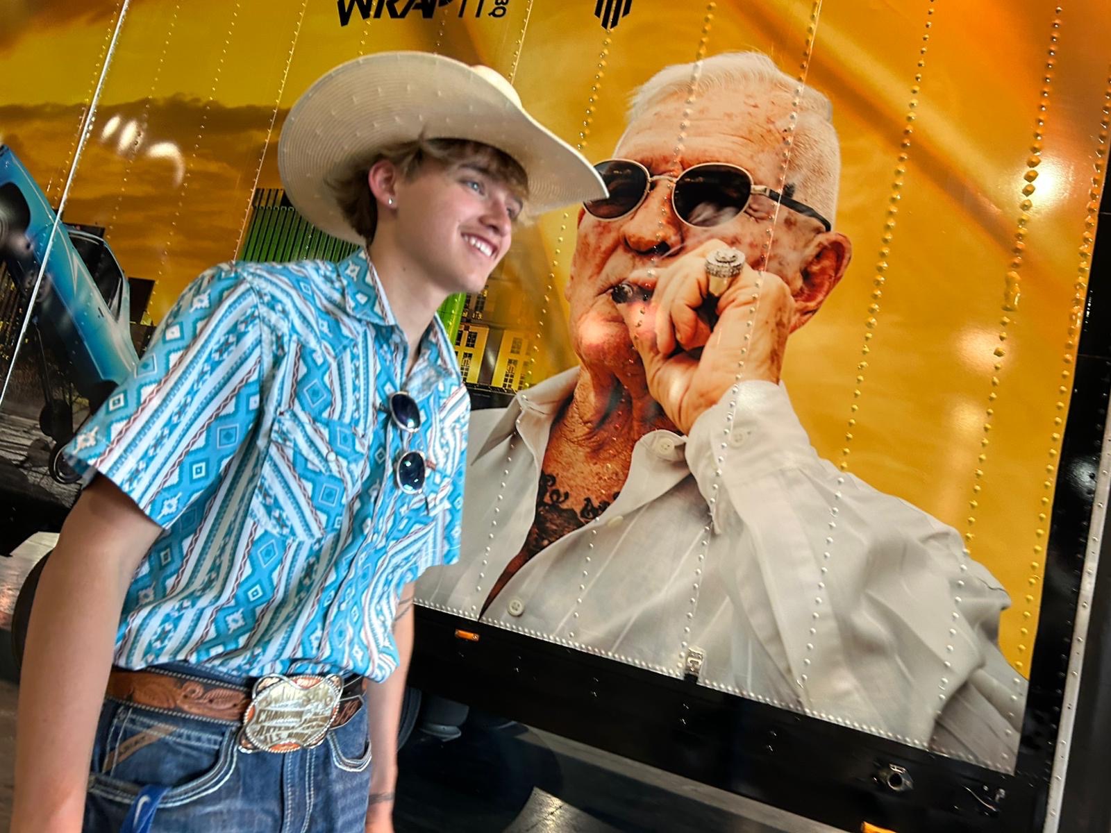 Young person in cowboy hat next to the Nuevo Movimiento truck wrap